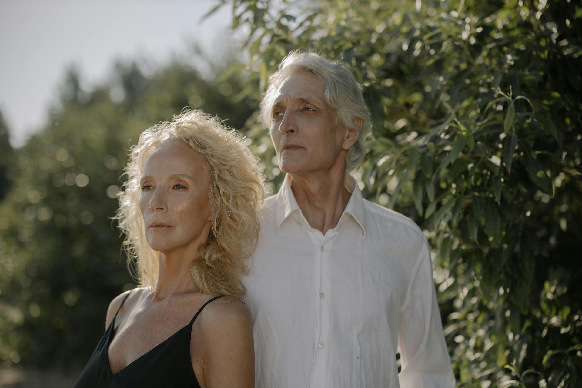 Serene portrait of a senior couple in lush greenery, looking into the distance.