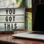 Lit sign with 'You Got This' alongside laptop on office desk.