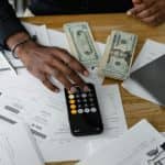 Overhead view of financial documents with calculator, cash, and laptop for financial planning.