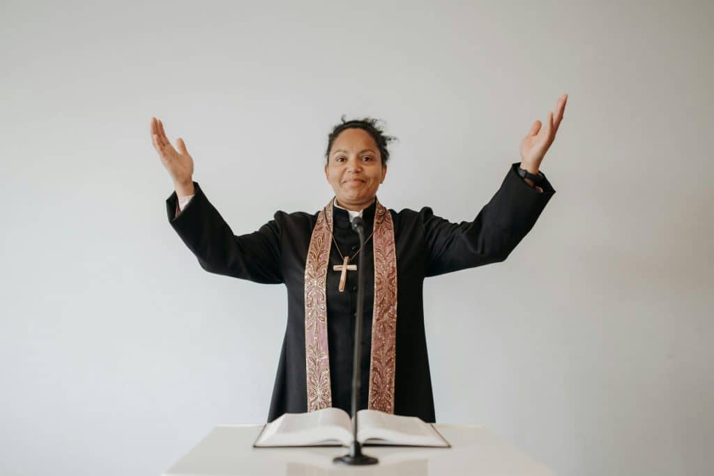 African American pastor with raised hands delivering a sermon in church.