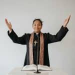 African American pastor with raised hands delivering a sermon in church.